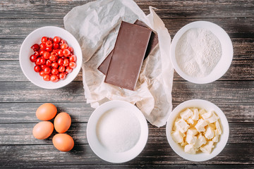 ingredients for brownie or chocolate cake muffins with cherry on wooden table, top view