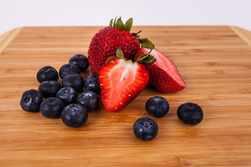 Strawberries blue berries on light wood bamboo cutting board