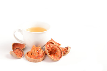 Slices of dry bael fruit and cup of dried bael juice on white background. (Aegle marmelos)