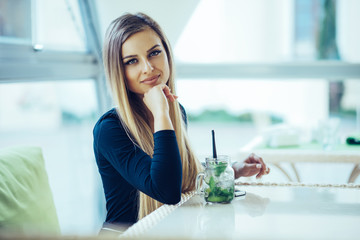 Beautiful young woman in cafe drinking mojito. Delicious refreshing cocktail on sunny day. Fruit drinks. Fresh juice. Woman relaxing on a summer day