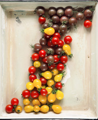 Fresh yellow, red and brown tomatoes from the market in a vintage tray, can be used as background