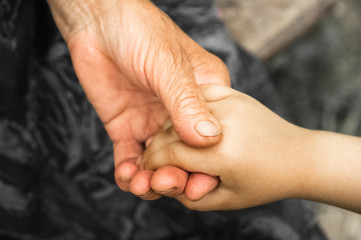 Fototapeta premium Hands of a little girl and an old grandmother. Hands of a little kids holding elderly man, World Kindness Day concept