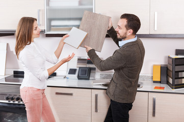 Salesman offering female client material for kitchen furniture