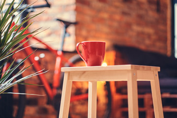Minimalism concept. Close-up image of a red cup on a wooden stool on a room with a loft interior.