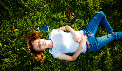 woman lying in grass listening to music - summertime relaxation