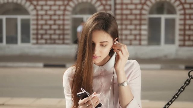 Young Stylish Pretty Girl with Phone posing in the city Streets. Teen Model wiht Headphones.