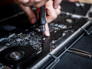 hand holding tweezers and screwdriver repairing the laptop close up computer fixing concept