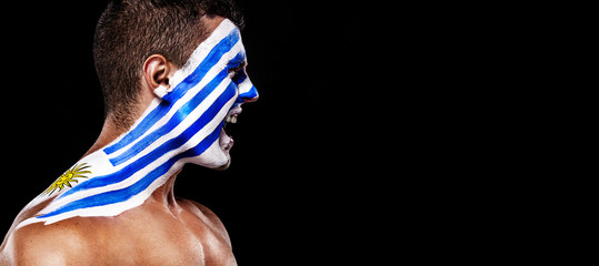 Soccer or football fan with bodyart on face with agression - flag of Uruguay.
