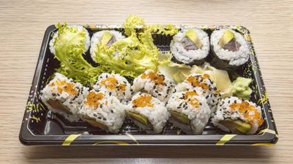 Japanese Cuisine: Tasty Uramaki and Futo Maki served in the take-away box - selective focus