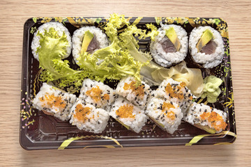 Japanese Cuisine: Tasty Uramaki and Futo Maki served in the take-away box - selective focus