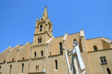 Fototapeta premium Ville de Salon-de-Provence, Collégiale Saint-Laurent (abrite le tombeau de Nostradamus) et statue représentant un personnage jouant de la harpe, département des Bouches-du-Rhône, France