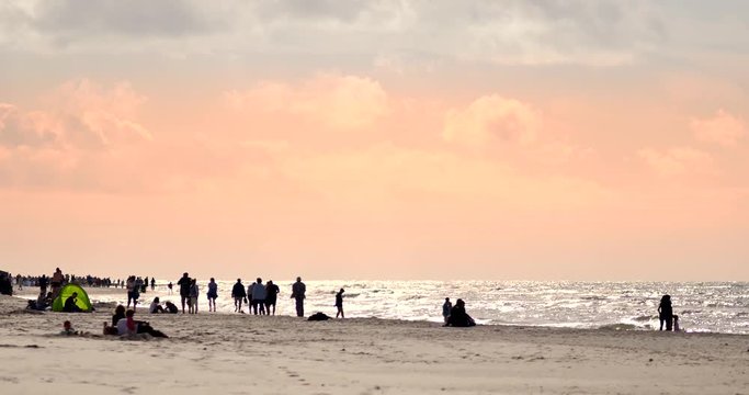 People relaxing on the beach of Baltic Sea at sunset.