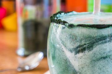 Closeup view fresh kefir probiotik drink in clear glass mixed with green spirulina powder on...