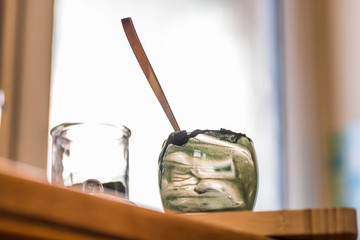 Closeup view emptied glass of fresh kefir probiotik drink mixed with green spirulina powder with spoon inside on kitchen table