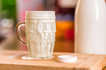 Closeup view fresh kefir probiotik drink emerged from overfilled empty glass on kitchen table