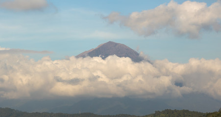 The peak of Agung volcano in the clouds in the evening