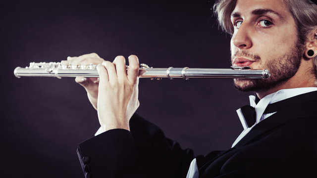 Elegantly dressed male musician playing flute