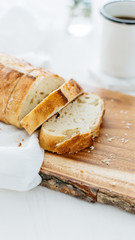 Loaf of bread sliced on wood cutting board and white linen.