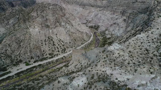 Aerial drone scene of Atuel river canyon in San Rafael, Mendoza, Cuyo Argentina. Camera moving forwards. Gravel street next trees and river. Colorfull rocks.