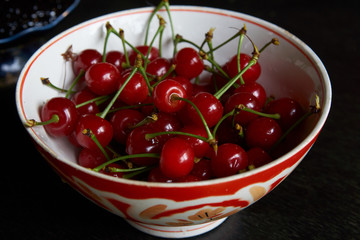 Bowl of fresh red cherries on dark background. Raw Red Organic Cherries food,  close-up, outdoors 