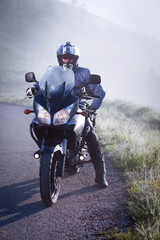 man riding a motorbike on foggy road in early morning