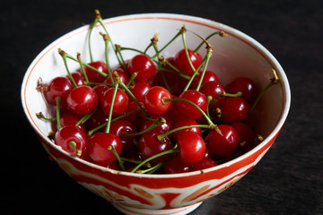 Bowl of fresh red cherries on dark background. Raw Red Organic Cherries food,  close-up, outdoors 