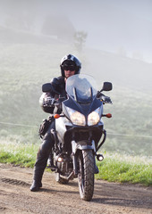 man riding a motorbike on foggy road in early morning