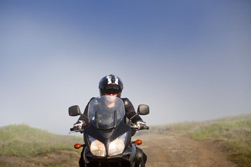 man riding a motorbike on foggy road in early morning