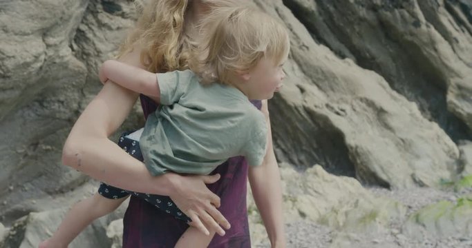 Mother on rocky beach with toddler boy