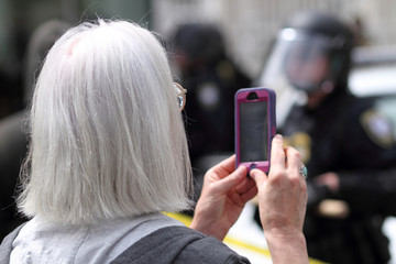 Protestor filming police with her cellphone.