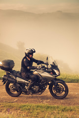 Fototapeta premium mężczyzna jedzie na motocyklu na mglistej drodze wczesnym rankiem