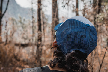 Back side of guy with curly hair and a hat in the forest