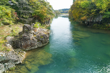 Fototapeta na wymiar 厳美渓のエメラルドグリーンの水流と秋の紅葉