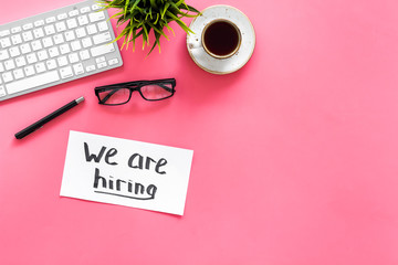 Search for worker, employee concept. We are hiring lettering on work desk on pink background top...