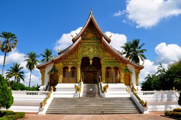 Buddhist temple in Asia against a blue sky background with palm trees. 