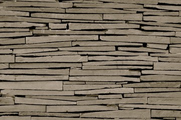 Close up detailed image of a modern dry stone wall made of irregular grey slabs