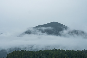 mountain covered in cloud in an overcast day with only the peak above the cloud