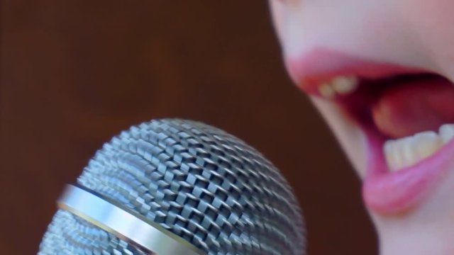 mouth of a boy singing into a close-up microphone