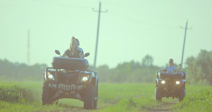 Girls riding on extreme quadrocycle ATV in a field off-road