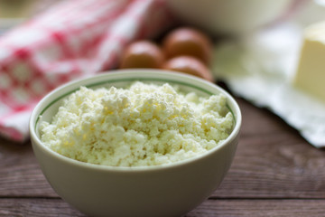 fresh rustic cottage cheese and eggs on wooden background, baking ingredients