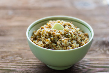 buckwheat porridge with butter in bowl on wooden background