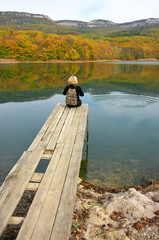 Hiker woman sitting over lake in autumnal day