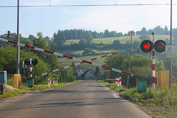 Road signs at the railway crossing with a barrier. Organization of the transport system of a European country. Red white coloring of anticipatory fog. Safety of traffic in road and rail transport.