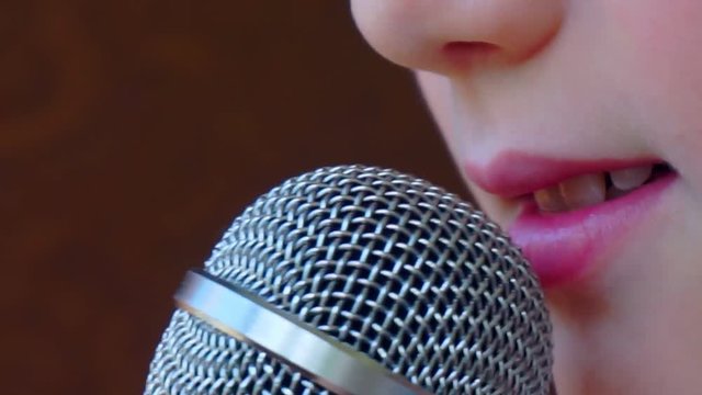 mouth of a boy singing into a close-up microphone
