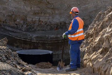 Builder at the construction site makes the sewage and water supply