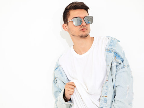 Portrait of handsome young model man dressed in jeans clothes in sunglasses posing on white background. Isolated