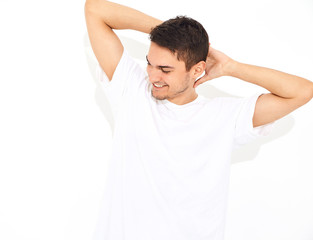 Portrait of handsome smiling young model man dressed in jeans clothes  and T-shirt posing on white background. Touching his head