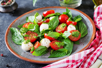 Caprese salad. Healthy meal with cherry tomatoes, mozzarella balls and basil. Home made, tasty food.  Concept for a tasty and healthy vegetarian meal.