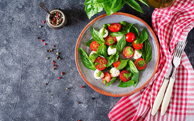 Caprese salad. Healthy meal with cherry tomatoes, mozzarella balls and basil. Home made, tasty food.  Concept for a tasty and healthy vegetarian meal. Top view. Flat lay