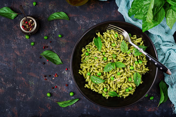Fusilli pasta with  pesto sauce, green peas and basil. Italian food. Top view. Flat lay.